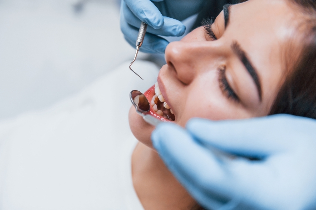 Dentist examining patient's teeth with dental mirror during examination for chipped tooth repair.