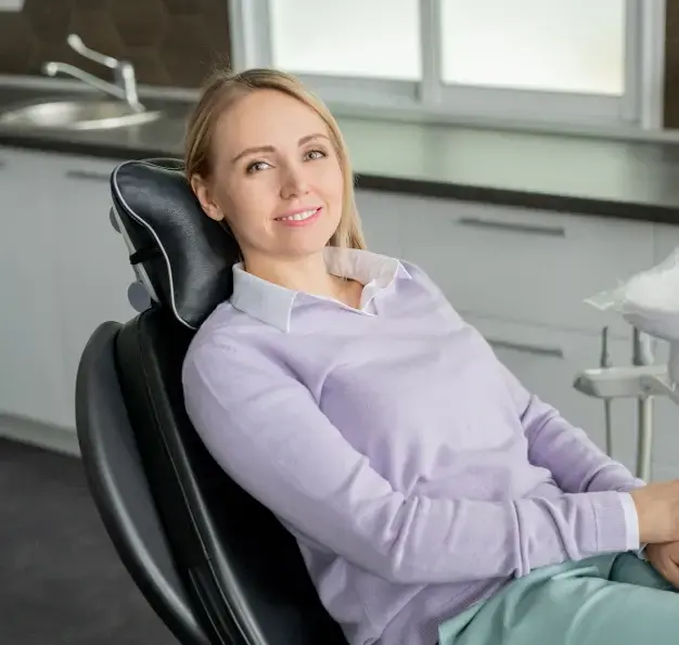 Smiling woman relaxing in dental chair during routine exam and cleaning appointment.