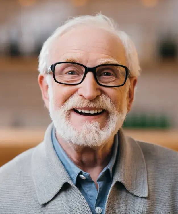 Smiling senior man with glasses in dental office setting for implant consultation.