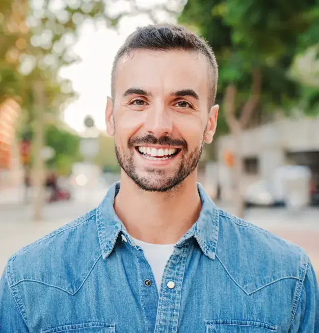 Smiling man in denim shirt at Sugar Land dental practice location.